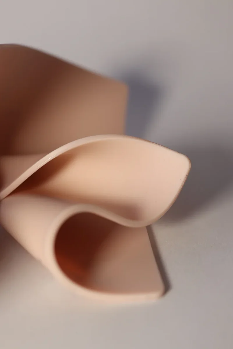 Flesh-tone FAKED SKIN practice pad folded to show its flexibility